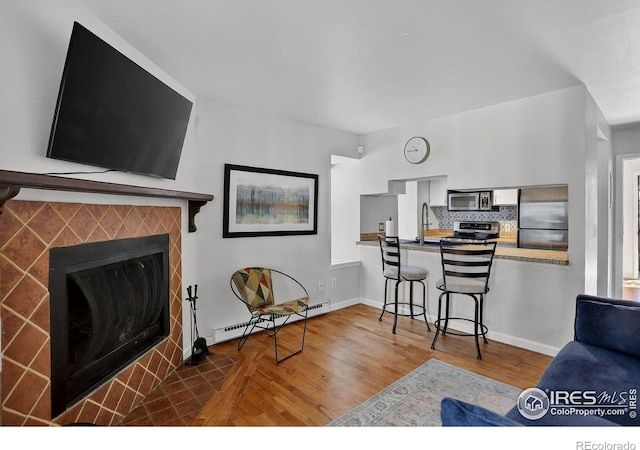 2279 Spruce St Unit 8, Boulder, CO 80302 - living room featuring a baseboard radiator, wood finished floors, and a tiled fireplace