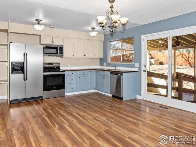 18931 E Brunswick Pl, Aurora, CO 80013 - kitchen with appliances with stainless steel finishes, dark wood-style floors, a chandelier, pendant lighting, and white cabinets