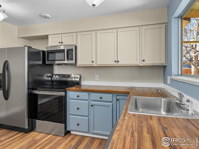 18931 E Brunswick Pl, Aurora, CO 80013 - kitchen featuring butcher block countertops, stainless steel appliances, blue cabinetry, and white cabinets