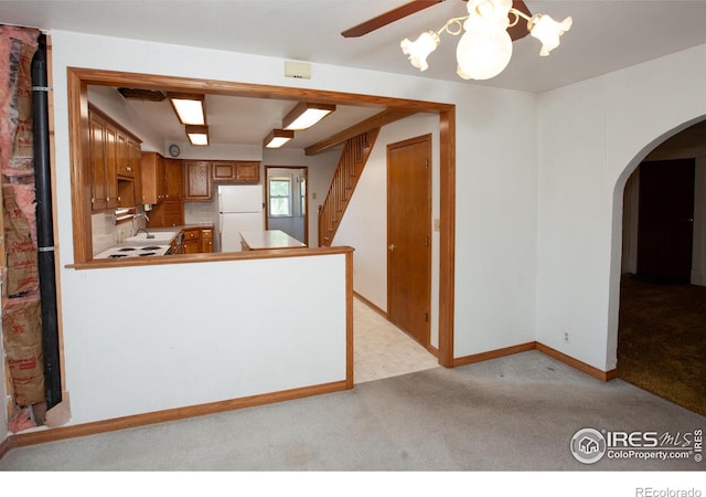 19089 Chambers Dr, Sterling, CO 80751 - kitchen with freestanding refrigerator, arched walkways, light colored carpet, ceiling fan, and brown cabinets