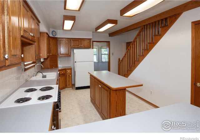 19089 Chambers Dr, Sterling, CO 80751 - kitchen featuring white appliances, light floors, brown cabinetry, and backsplash