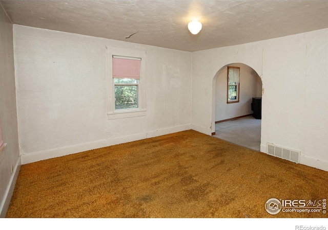 19089 Chambers Dr, Sterling, CO 80751 - unfurnished room with arched walkways, carpet, plenty of natural light, and a textured ceiling