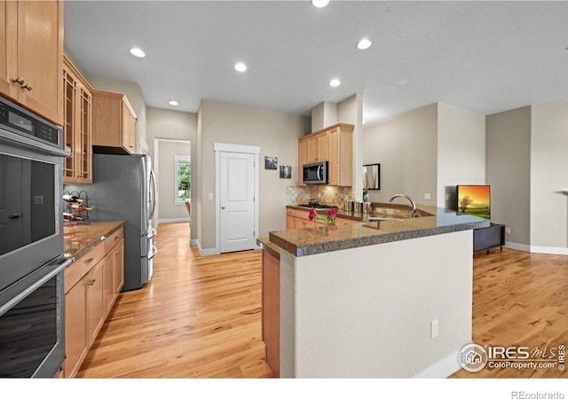 3031 Thunder Lake Cir, Lafayette, CO 80026 - kitchen with appliances with stainless steel finishes, light wood finished floors, glass insert cabinets, light brown cabinets, and tasteful backsplash