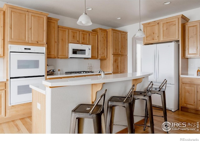 6771 Crooked Stick Dr, Windsor, CO 80550 - kitchen featuring white appliances, light wood-type flooring, a breakfast bar, light countertops, and recessed lighting