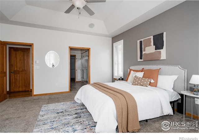 6771 Crooked Stick Dr, Windsor, CO 80550 - carpeted bedroom featuring a tray ceiling, connected bathroom, and ceiling fan