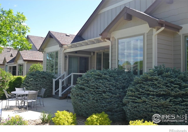 6771 Crooked Stick Dr, Windsor, CO 80550 - view of side of home with a patio, roof with shingles, and board and batten siding