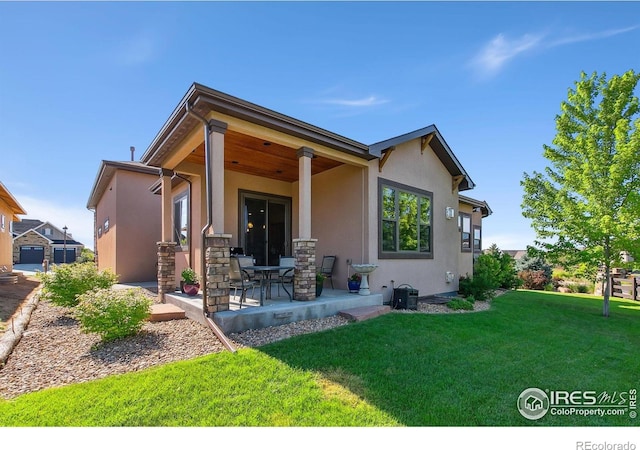 973 Skipping Stone Ct, Timnath, CO 80547 - back of house featuring stucco siding, a lawn, and a patio area