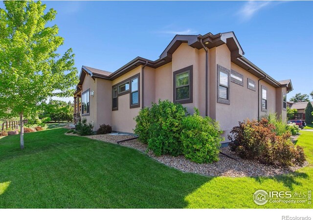 973 Skipping Stone Ct, Timnath, CO 80547 - view of side of home featuring stucco siding and a yard