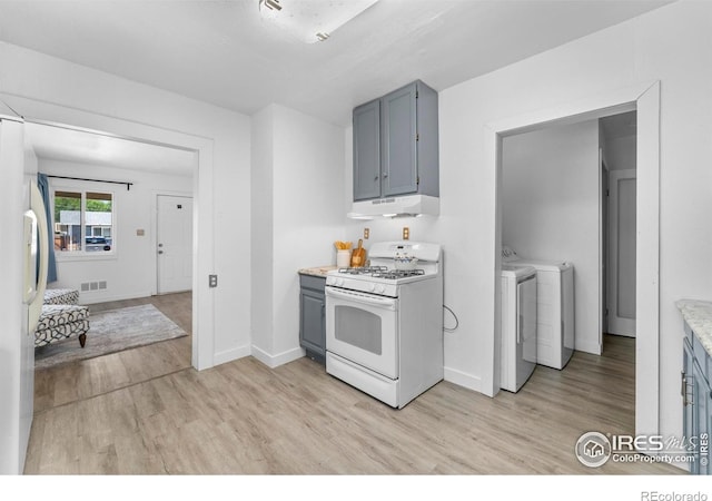 114 Berwick Ave, Firestone, CO 80520 - kitchen featuring white gas range, refrigerator with ice dispenser, under cabinet range hood, washer and clothes dryer, and light wood finished floors
