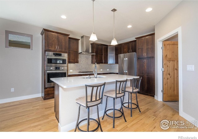 6928 Summerwind Ct, Timnath, CO 80547 - kitchen featuring wall chimney exhaust hood, appliances with stainless steel finishes, light wood finished floors, decorative backsplash, and light countertops