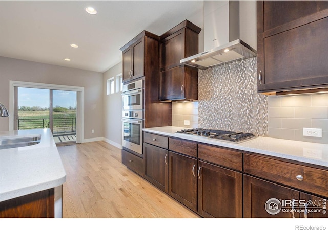 6928 Summerwind Ct, Timnath, CO 80547 - kitchen with wall chimney range hood, stainless steel appliances, light countertops, light wood-type flooring, and recessed lighting