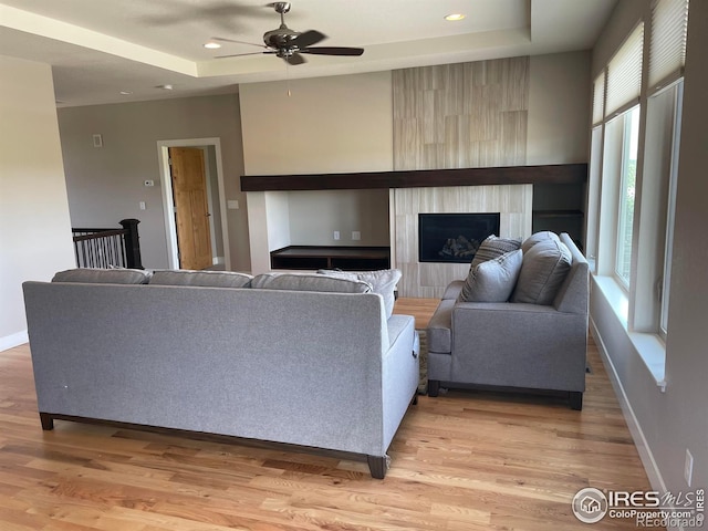 6928 Summerwind Ct, Timnath, CO 80547 - living room with a ceiling fan, a tray ceiling, light wood-style flooring, a fireplace, and recessed lighting