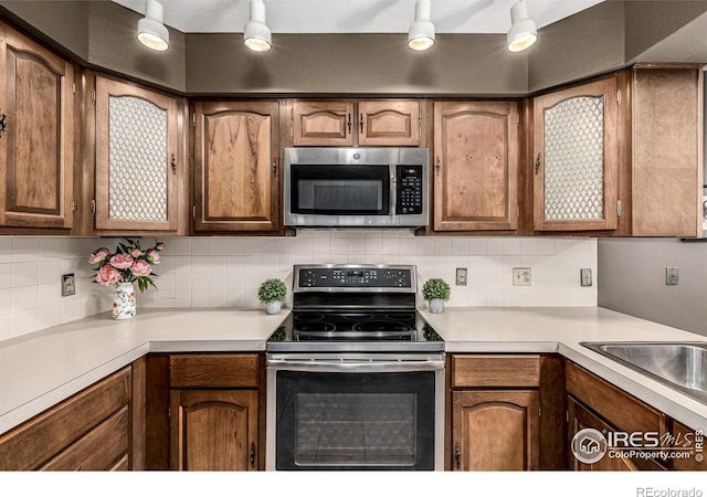 14 Douglas Dr N, Broomfield, CO 80020 - kitchen featuring appliances with stainless steel finishes, light countertops, tasteful backsplash, and brown cabinets