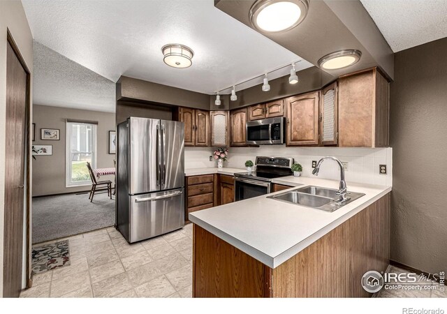 14 Douglas Dr N, Broomfield, CO 80020 - kitchen with appliances with stainless steel finishes, rail lighting, a peninsula, light countertops, and a textured ceiling