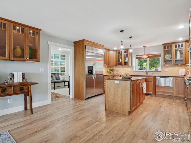 2695 Stanford Ave, Boulder, CO 80305 - kitchen featuring appliances with stainless steel finishes, light wood-style flooring, backsplash, a kitchen island, and brown cabinetry