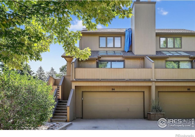 2954 Kalmia Ave # 34, Boulder, CO 80301 - view of front of home featuring an attached garage, a chimney, stairway, driveway, and a shingled roof