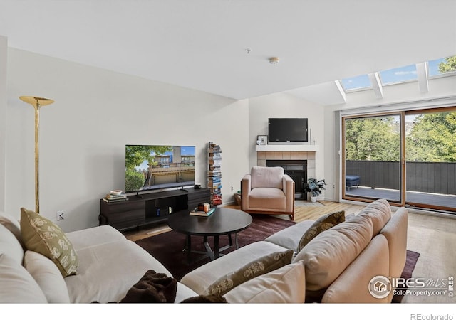 2954 Kalmia Ave # 34, Boulder, CO 80301 - living area featuring a tiled fireplace, a skylight, wood finished floors, and vaulted ceiling