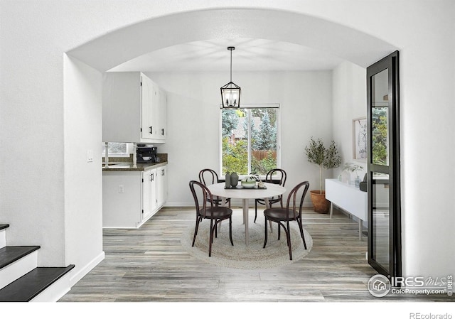 2078 Goldfinch Ct, Longmont, CO 80503 - dining room with light wood finished floors, arched walkways, a chandelier, and stairs