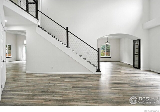2078 Goldfinch Ct, Longmont, CO 80503 - unfurnished living room with a towering ceiling, arched walkways, wood finished floors, and stairs