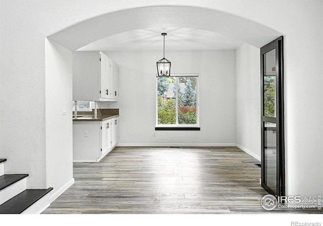 2078 Goldfinch Ct, Longmont, CO 80503 - kitchen with dark countertops, arched walkways, wood finished floors, and white cabinets