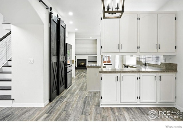 2078 Goldfinch Ct, Longmont, CO 80503 - kitchen featuring white cabinets, light wood-type flooring, freestanding refrigerator, a barn door, and recessed lighting