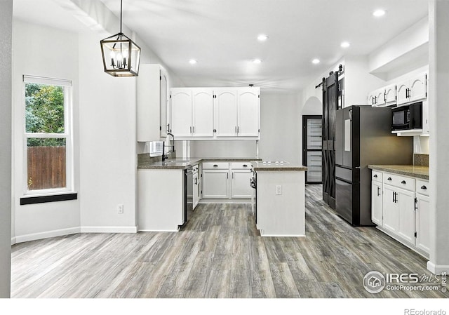 2078 Goldfinch Ct, Longmont, CO 80503 - kitchen with a barn door, black microwave, dark countertops, a center island, and light wood-style floors