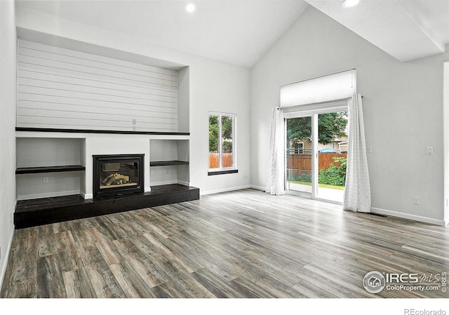 2078 Goldfinch Ct, Longmont, CO 80503 - unfurnished living room featuring high vaulted ceiling, wood finished floors, a glass covered fireplace, and recessed lighting