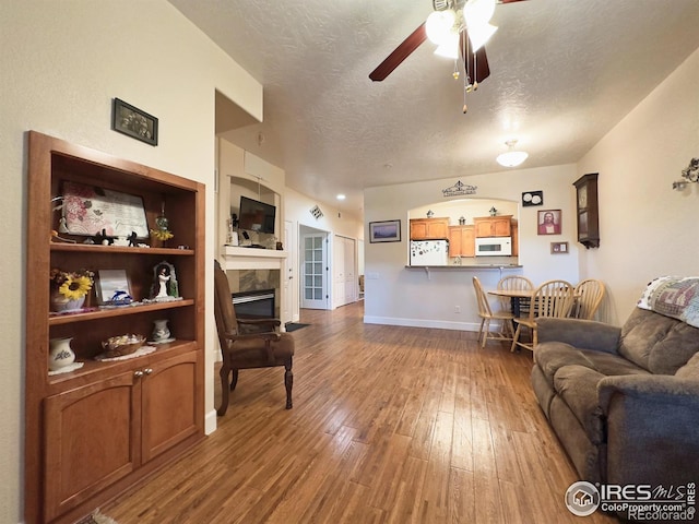 4101 Crittenton Ln Unit 102, Wellington, CO 80549 - living room featuring ceiling fan, wood finished floors, a tile fireplace, and a textured ceiling