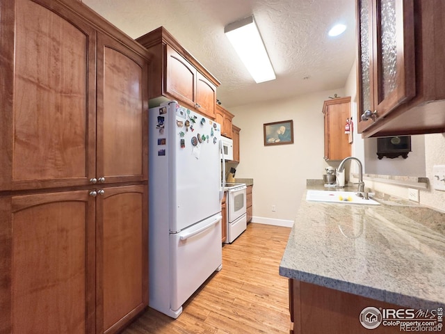 4101 Crittenton Ln Unit 102, Wellington, CO 80549 - kitchen with white appliances, light wood-style flooring, a textured ceiling, and brown cabinetry