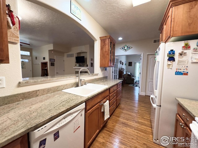 4101 Crittenton Ln Unit 102, Wellington, CO 80549 - kitchen featuring white appliances, brown cabinetry, a textured ceiling, wood finished floors, and arched walkways