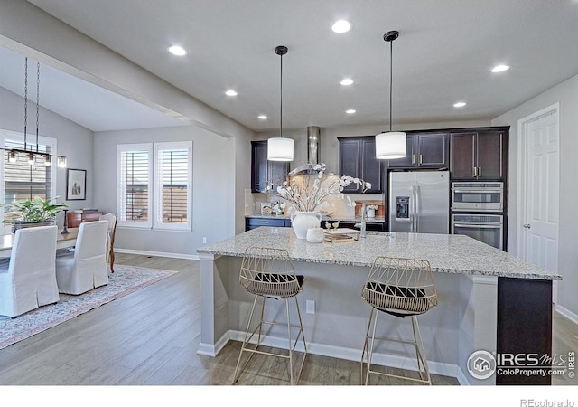 16021 Williams Pl, Broomfield, CO 80023 - kitchen with stainless steel appliances, a chandelier, wall chimney range hood, light wood-type flooring, and recessed lighting