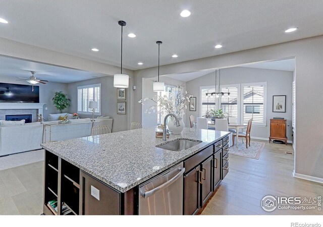 16021 Williams Pl, Broomfield, CO 80023 - kitchen featuring stainless steel dishwasher, ceiling fan, a fireplace, an island with sink, and open floor plan