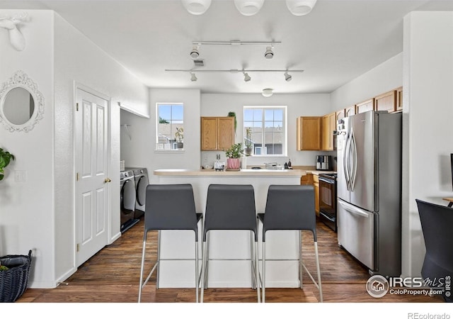 14700 E 104th Ave Unit 2605, Commerce City, CO 80022 - kitchen featuring freestanding refrigerator, washing machine and clothes dryer, black range with electric stovetop, a kitchen island, and a breakfast bar