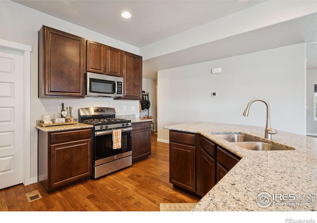1325 Tipton St, Berthoud, CO 80513 - kitchen featuring stainless steel appliances, wood finished floors, light stone countertops, dark brown cabinets, and recessed lighting