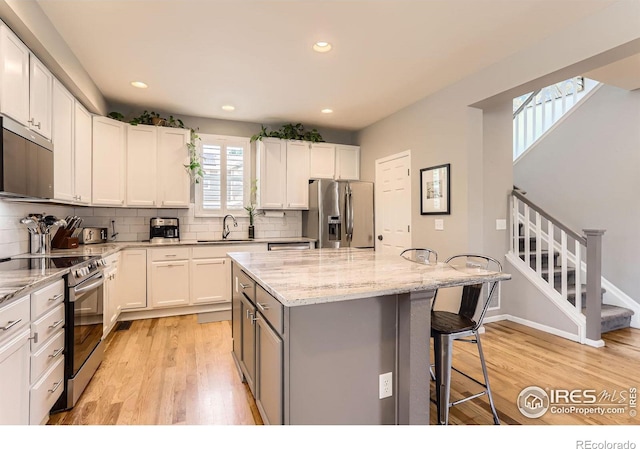 549 Jackson St, Lafayette, CO 80026 - kitchen with stainless steel appliances, a breakfast bar area, light wood finished floors, light stone counters, and recessed lighting