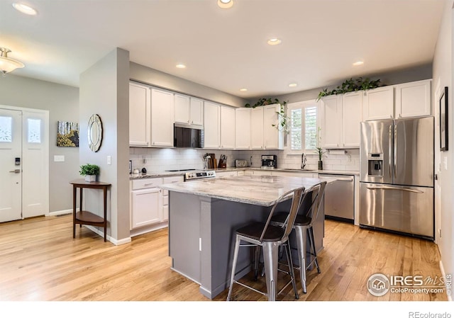 549 Jackson St, Lafayette, CO 80026 - kitchen featuring stainless steel appliances, light wood-style flooring, light stone countertops, a kitchen breakfast bar, and recessed lighting