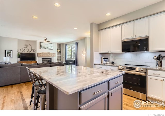 549 Jackson St, Lafayette, CO 80026 - kitchen featuring appliances with stainless steel finishes, light wood-type flooring, a center island, open floor plan, and recessed lighting