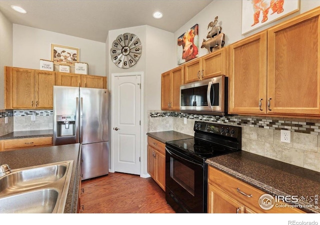 1520 Lake Vista Way, Severance, CO 80550 - kitchen with stainless steel appliances, dark countertops, wood finished floors, decorative backsplash, and recessed lighting