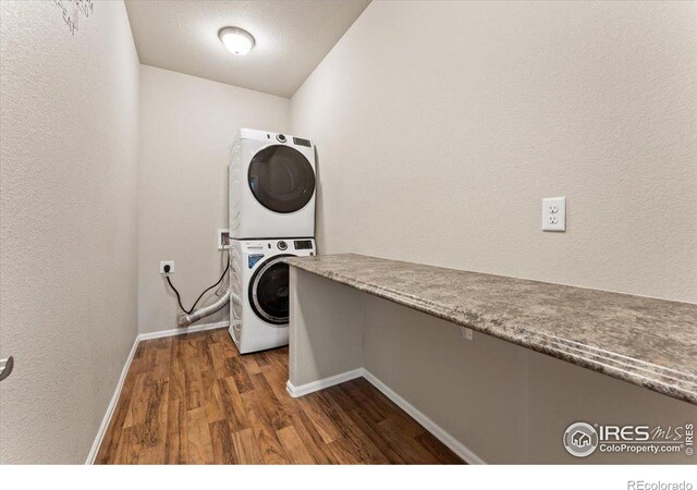 1520 Lake Vista Way, Severance, CO 80550 - laundry area featuring stacked washer and clothes dryer, dark wood-style flooring, and a textured wall