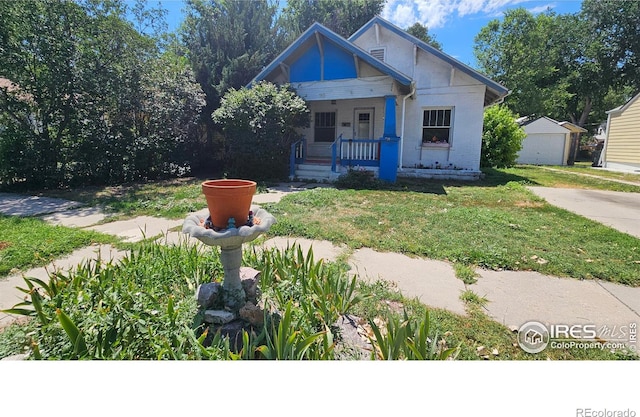 710 Carson St, Brush, CO 80723 - bungalow featuring a porch, a front lawn, and an outbuilding