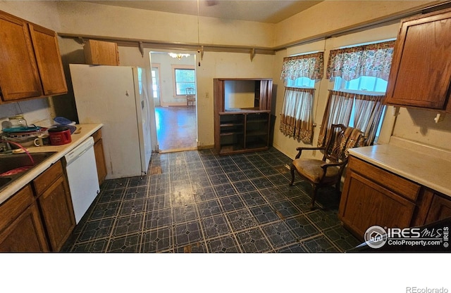 710 Carson St, Brush, CO 80723 - kitchen featuring white appliances, dark flooring, brown cabinets, and light countertops