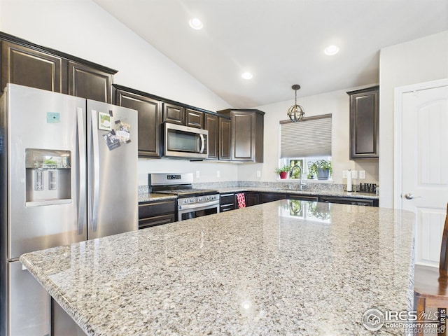 1729 Avery Plaza St, Severance, CO 80550 - kitchen featuring stainless steel appliances, lofted ceiling, dark brown cabinetry, light stone counters, and a center island