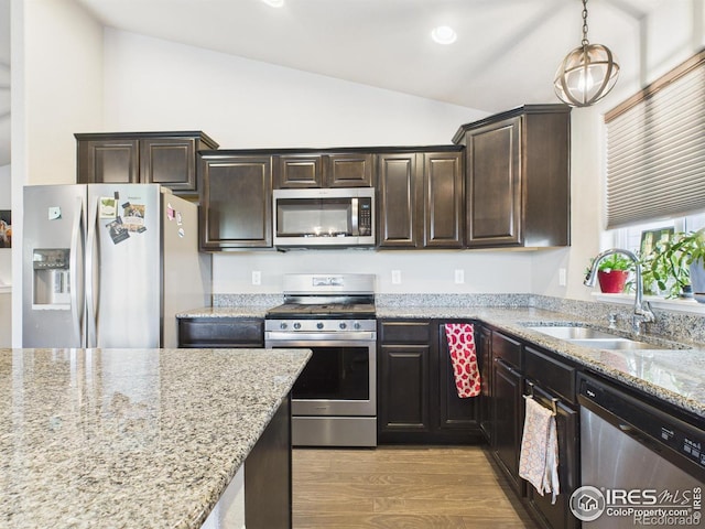 1729 Avery Plaza St, Severance, CO 80550 - kitchen featuring vaulted ceiling, stainless steel appliances, light wood-type flooring, dark brown cabinetry, and light stone countertops