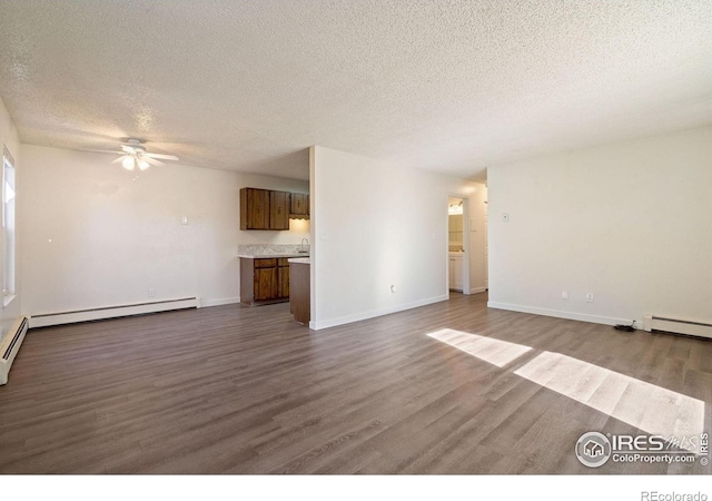 1620-1626 E 17th St, Loveland, CO 80538 - unfurnished living room with a textured ceiling, dark wood-style floors, a ceiling fan, a baseboard radiator, and baseboard heating