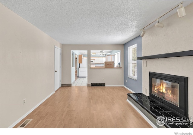 11450 Hudson St, Thornton, CO 80233 - unfurnished living room with wood finished floors, a textured ceiling, a tiled fireplace, and a ceiling fan
