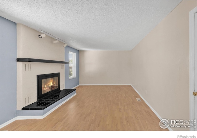11450 Hudson St, Thornton, CO 80233 - unfurnished living room featuring a textured ceiling, wood finished floors, and a tiled fireplace