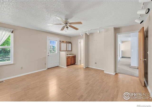 11450 Hudson St, Thornton, CO 80233 - unfurnished living room with a ceiling fan, light wood finished floors, a textured ceiling, and plenty of natural light