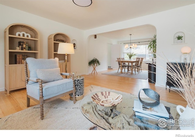 1539 Peterson St, Fort Collins, CO 80524 - living area with wood finished floors, a chandelier, arched walkways, and built in shelves