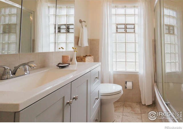 1539 Peterson St, Fort Collins, CO 80524 - bathroom featuring tile walls, vanity, and combined bath / shower with glass door