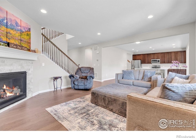 6244 Waterman Way, Frederick, CO 80516 - living room featuring wood finished floors, a glass covered fireplace, stairs, and recessed lighting
